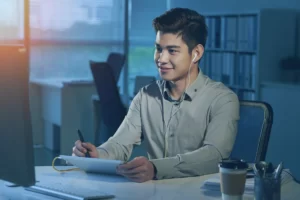 Young Filipino man wearing earphones working in an office.